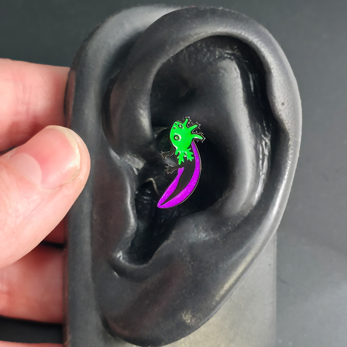 green and purple axolotl daith earring in ear