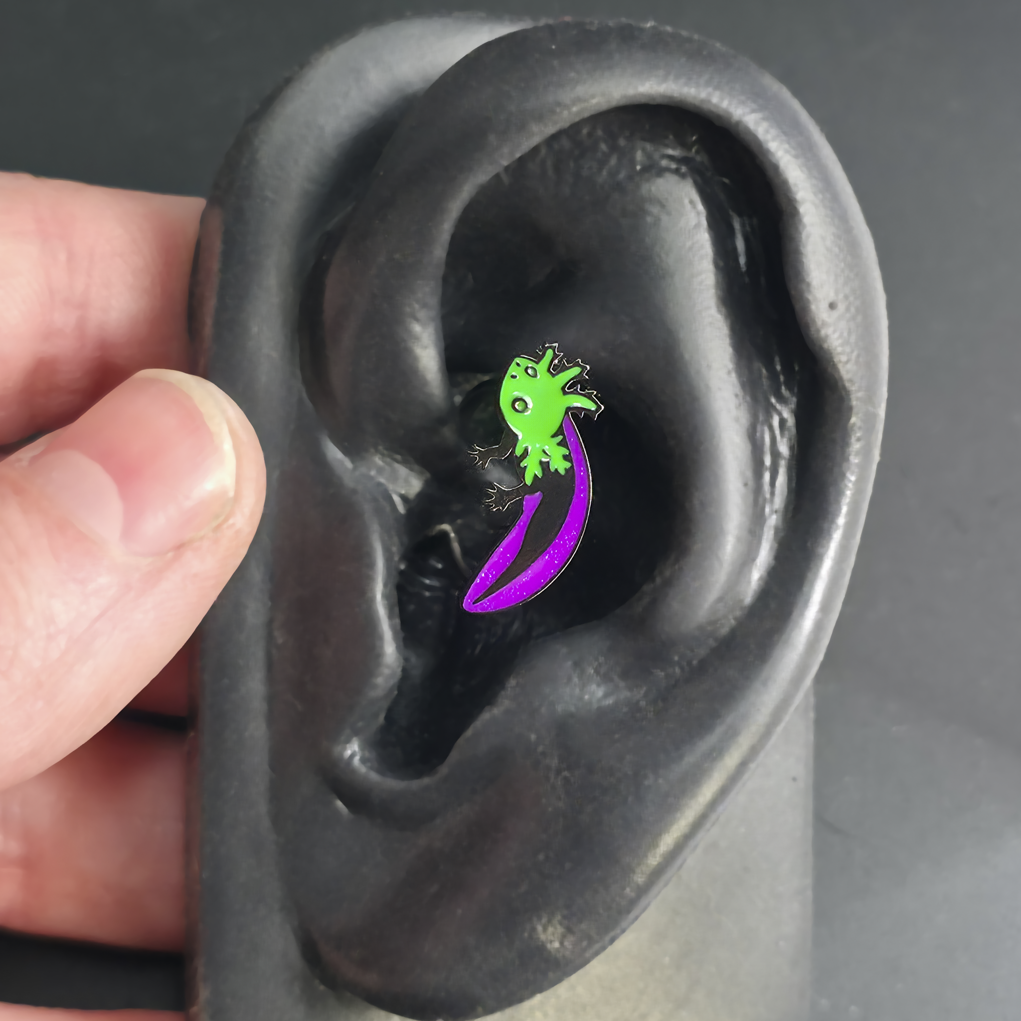 green and purple axolotl daith earring in ear