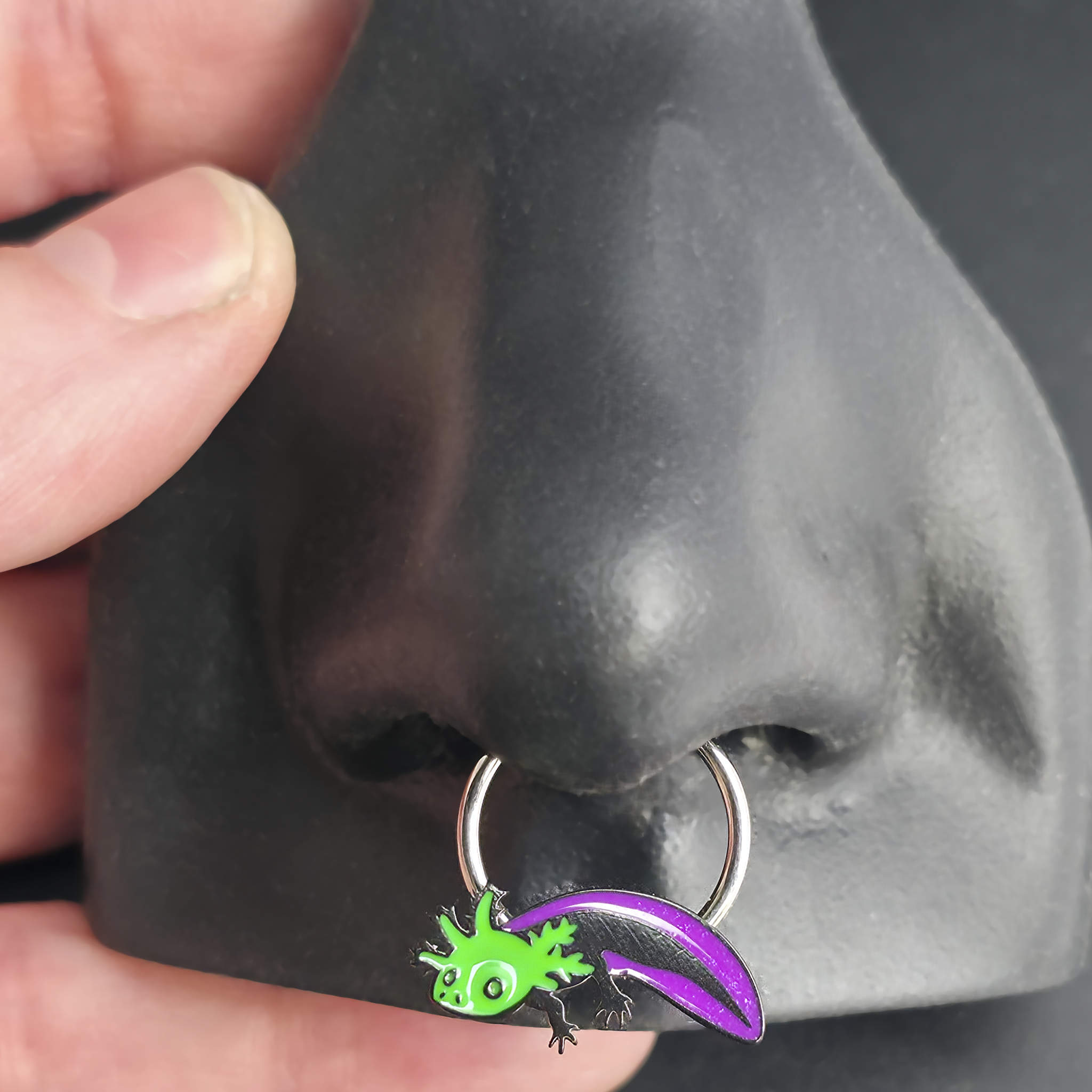 green and purple axolotl septum ring in nose