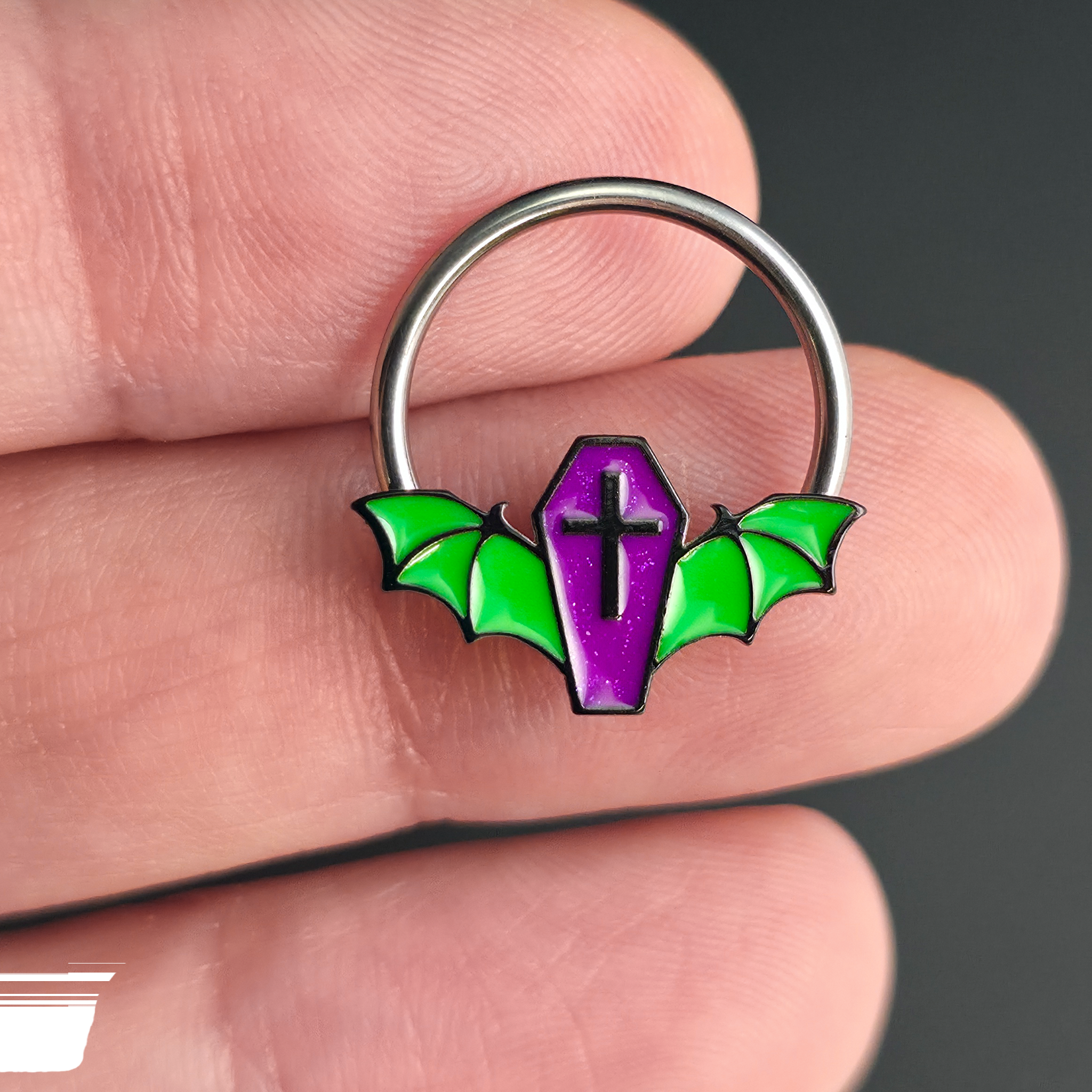 purple and green coffin bat septum ring on hand