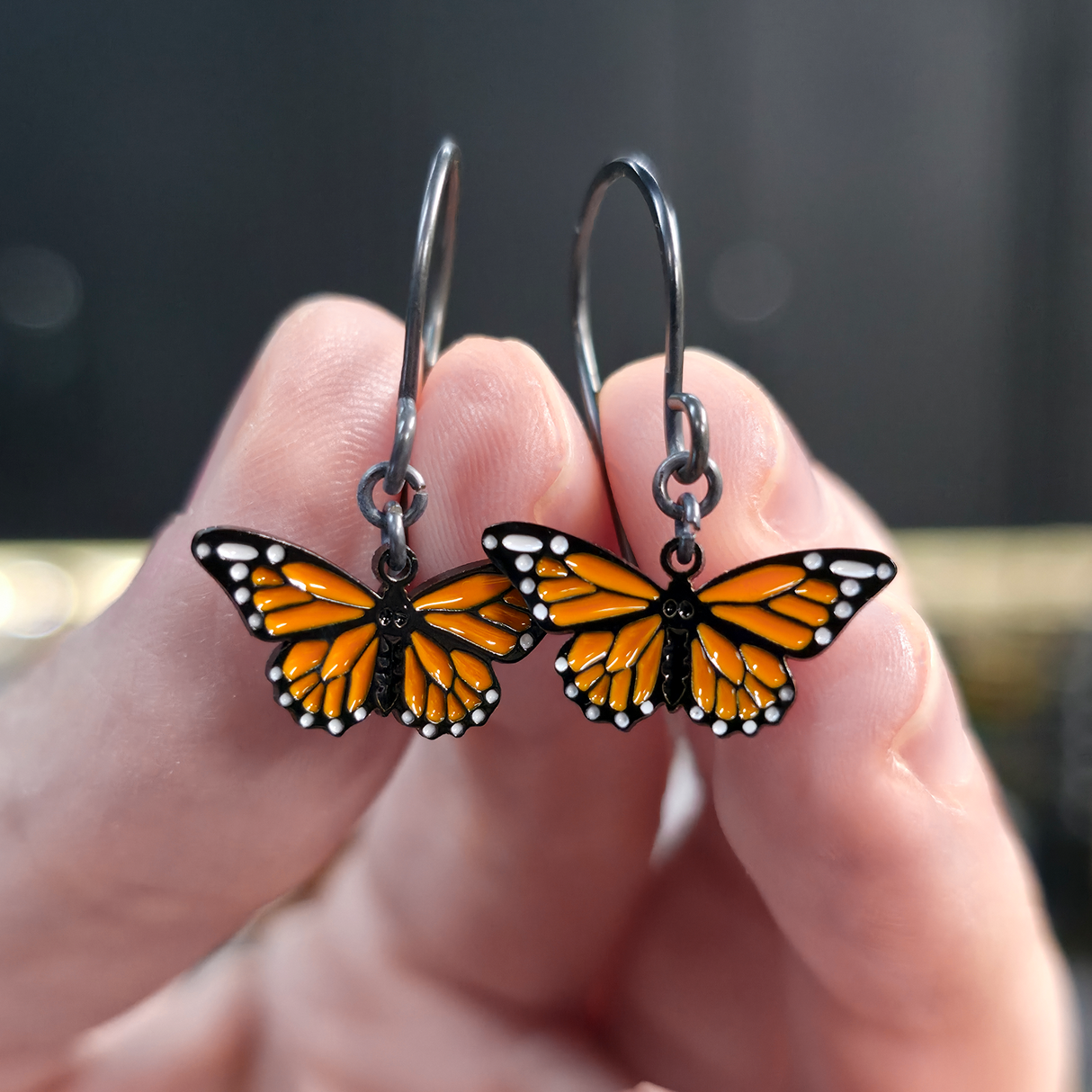 monarch butterfly dangle earrings held in fingers
