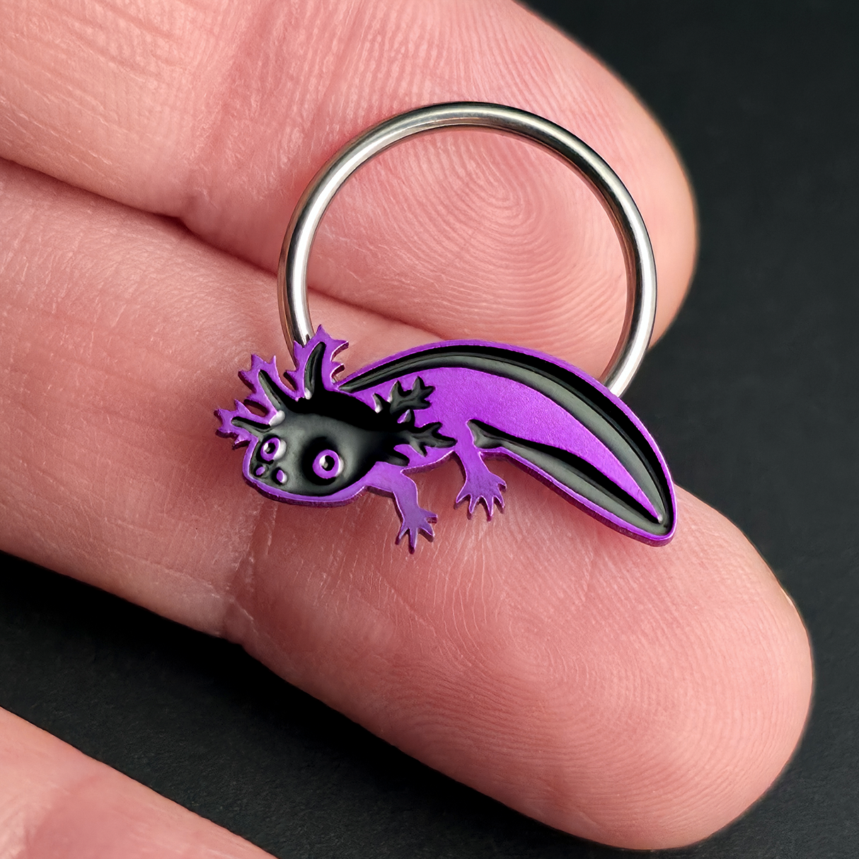 black and purple axolotl septum ring on hand