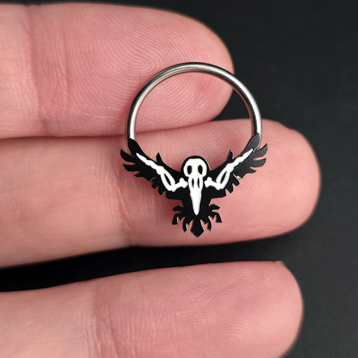 raven skeleton septum ring on hand