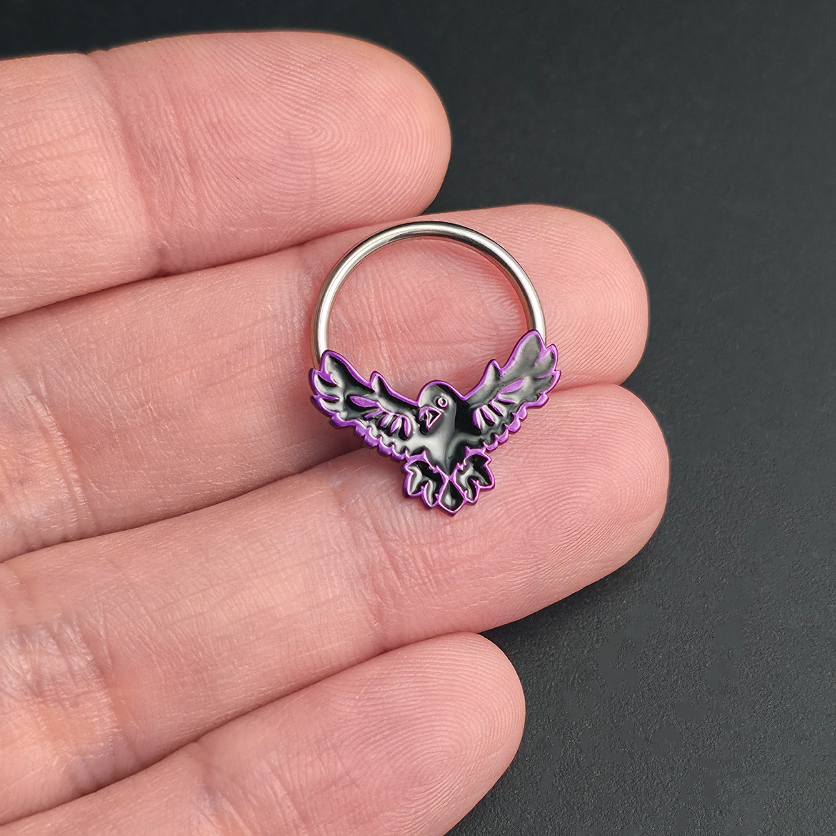 flying raven septum ring on hand