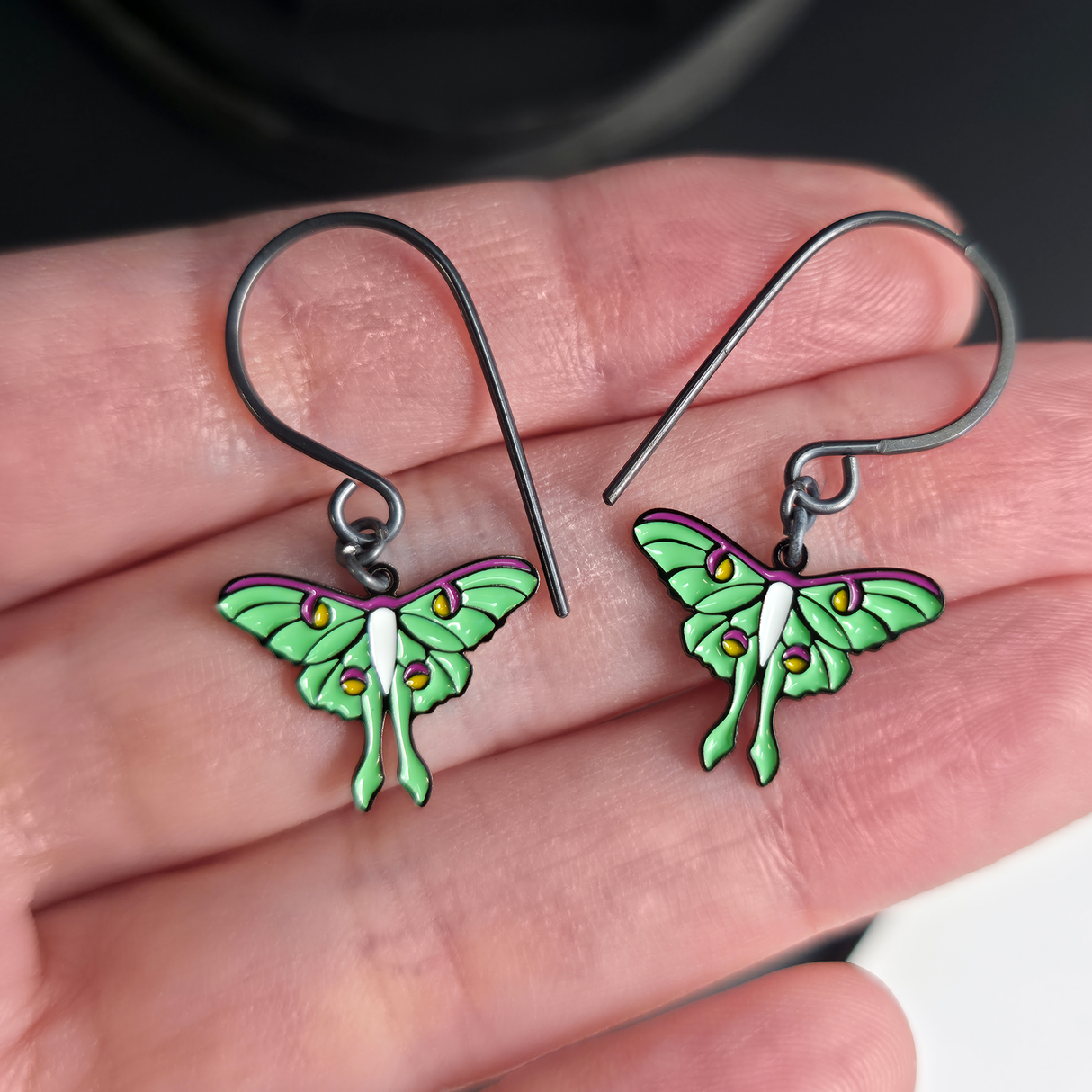 luna moth dangle earrings on hand